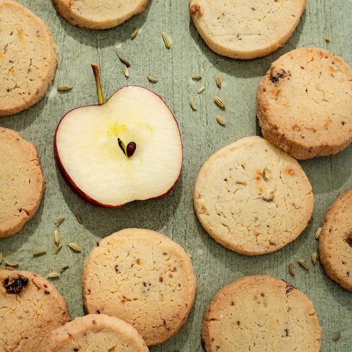 Apple and Fennel shortbread with an apple slice and fennel seeds on a green surface
