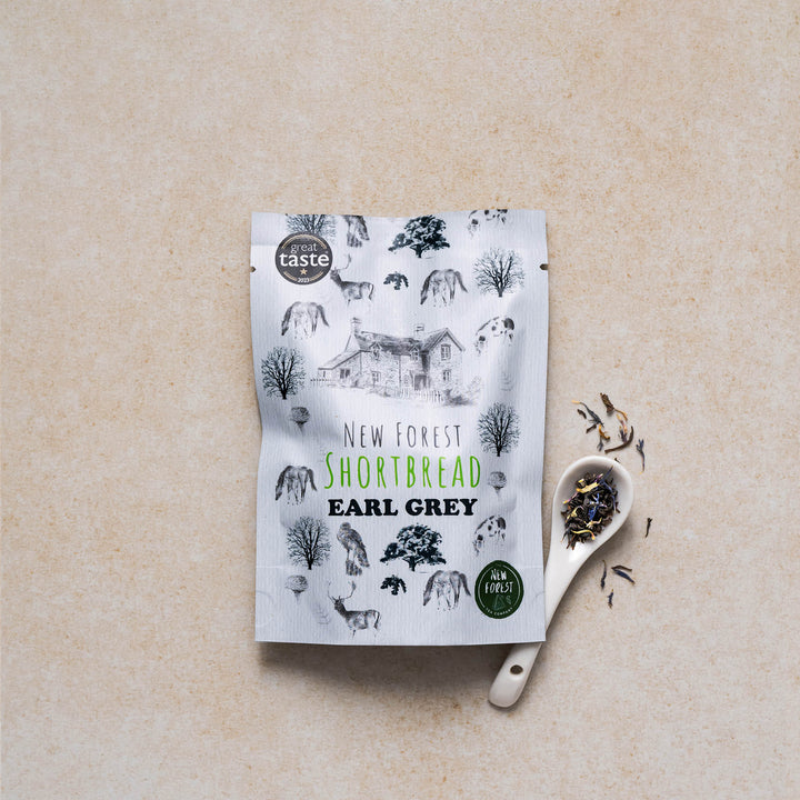 New Forest earl grey shortbread snack pack with a display of tea leaves on a spoon with a neutral backdrop