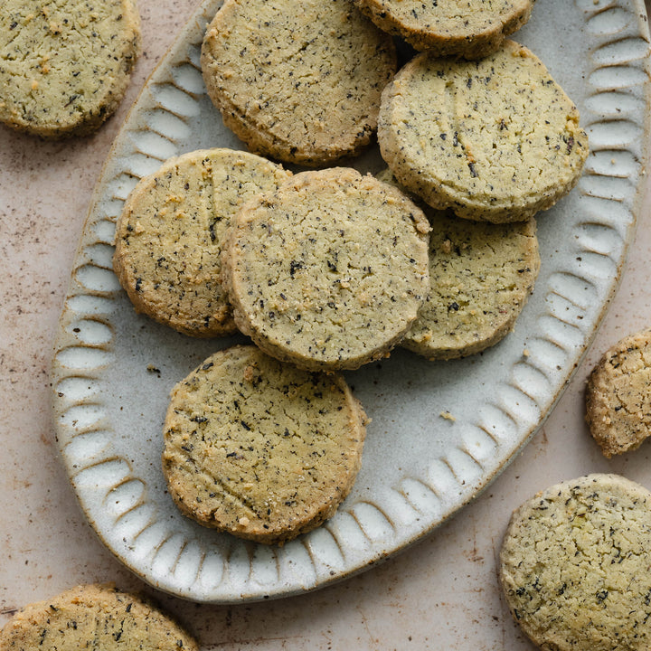Rounds of  earl grey shortbread on a decorative edged ceramic plate with a beige background