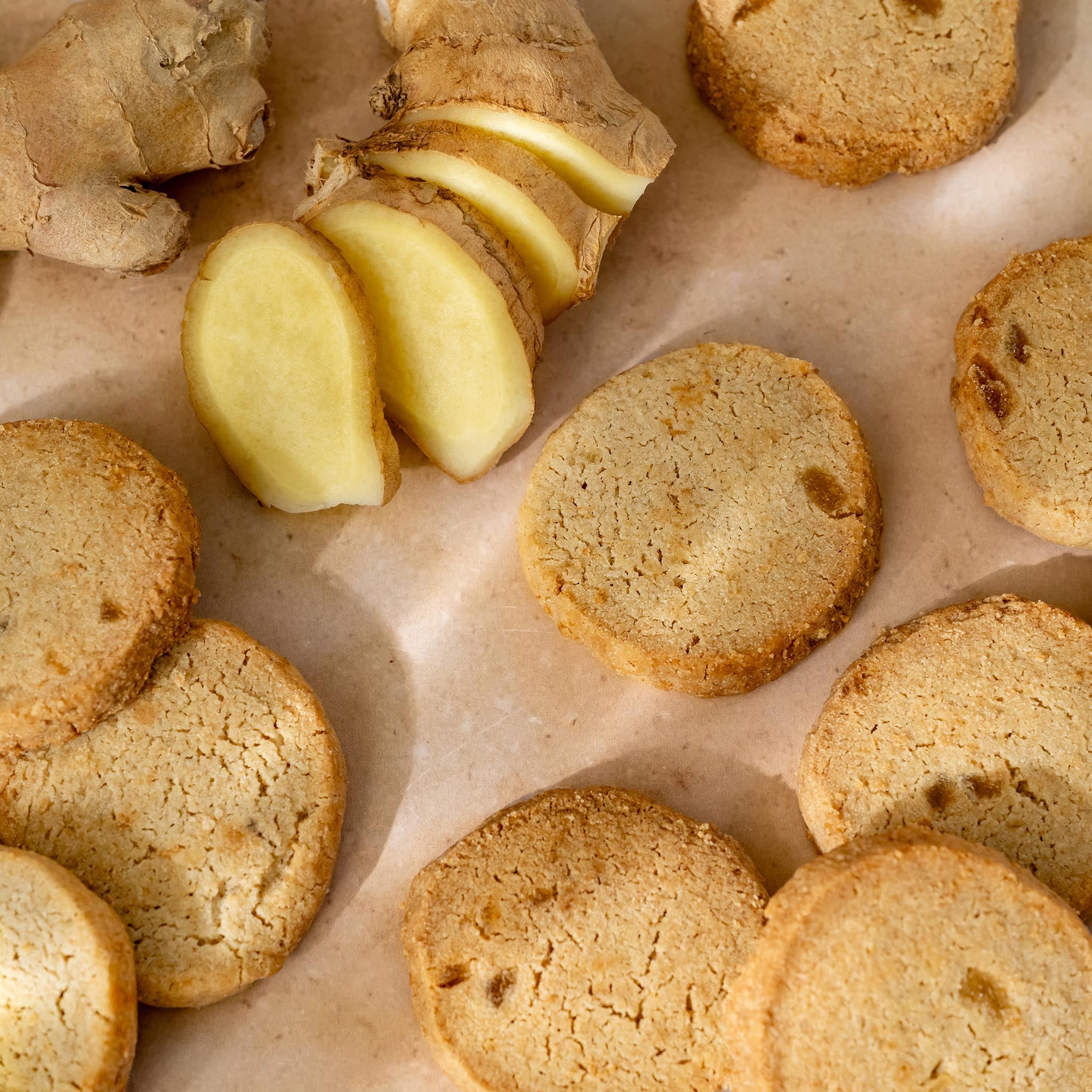 Ginger flavoured shortbread with sliced ginger on a brown surface