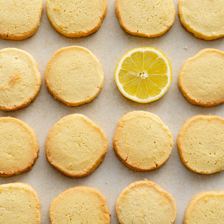 Row of lemon shortbread with a sliced lemon on a baking sheet