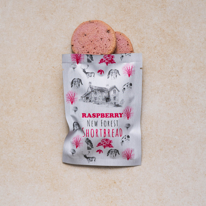  New Forest shortbread raspberry snack pack with a display of 2 raspberry cookies on a neutral backdrop