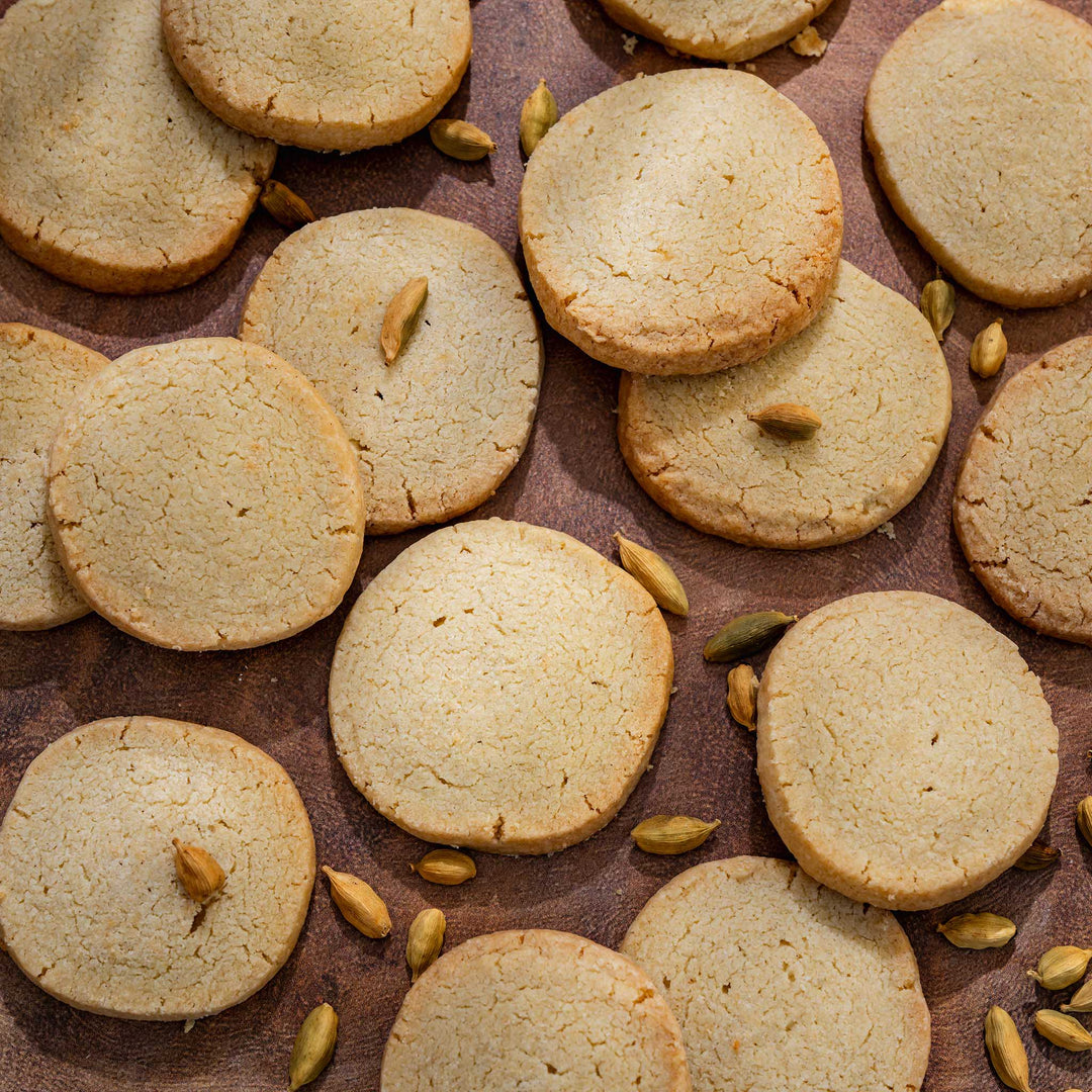 Round cardamon shortbread with cardamom seeds on a brown surface