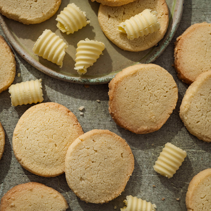 Buttery shortbread with curled shreds of butter on a stone plate on a rustic surface
