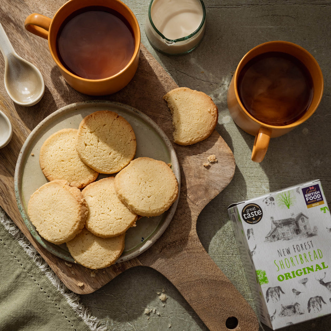 Plate of shortbread cookies with two cups of tea on a wooden board.